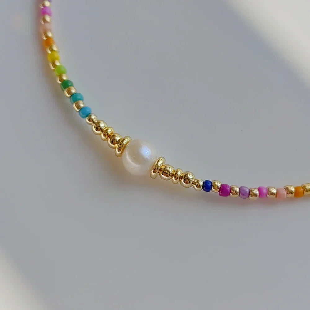 Naszyjnik typu choker z zawieszką w kształcie tęczy i perełkami
