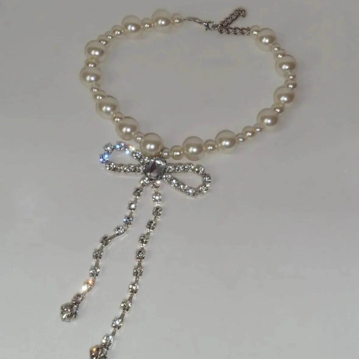 Naszyjnik typu choker z zawieszką w kształcie kokardy wysadzanej strasami